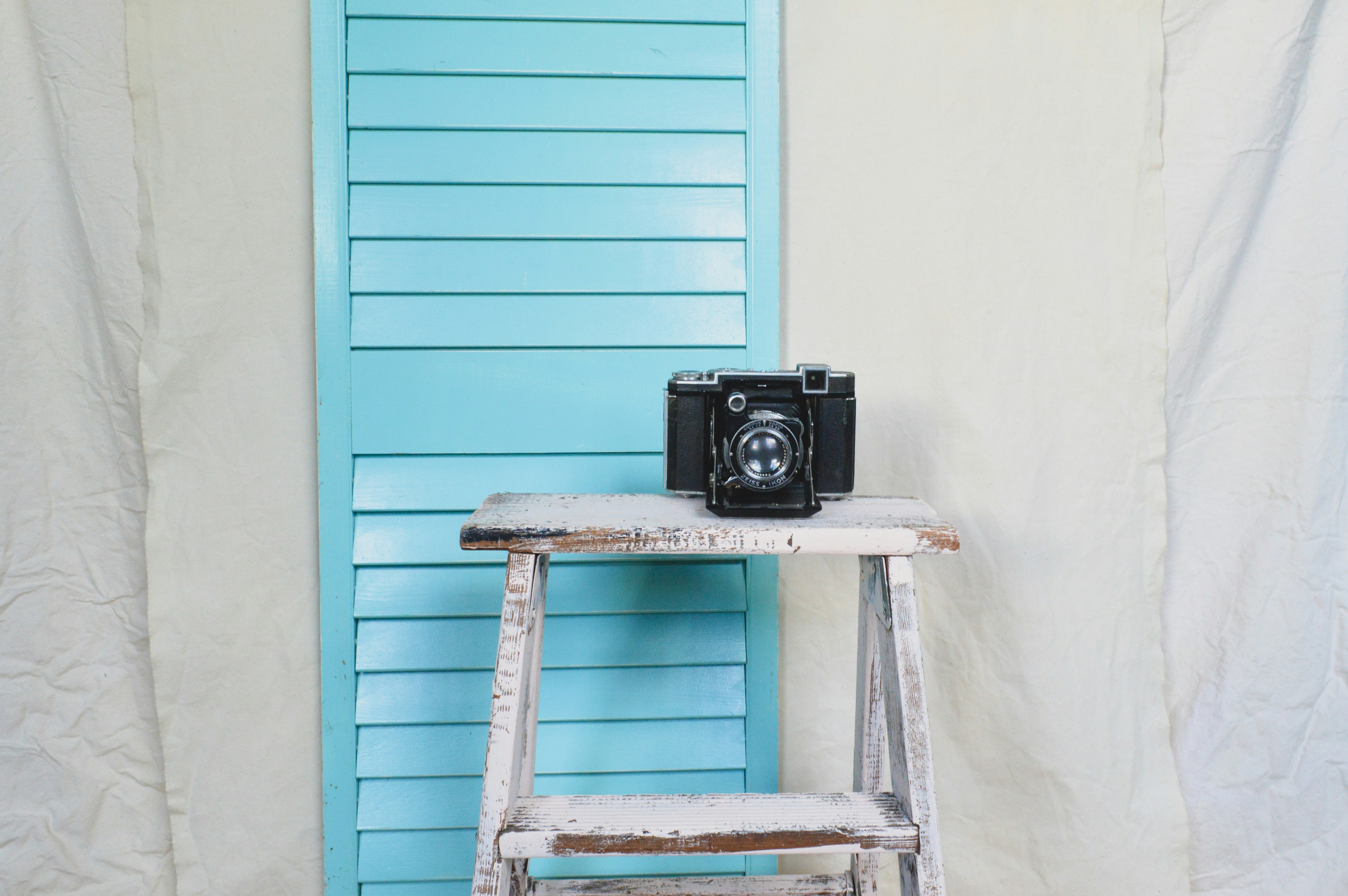 black and gray camera on blue wooden ladder